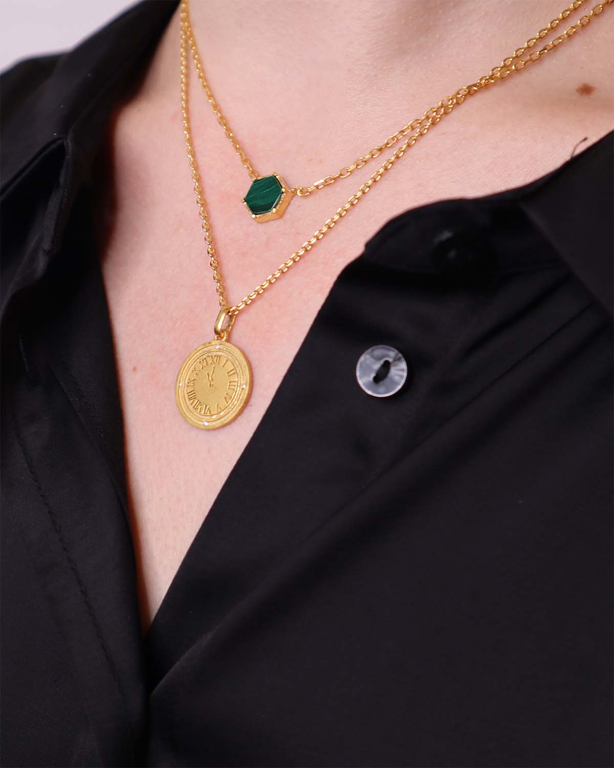 Close-up of a gold necklace with a natural malachite gemstone and wave texture