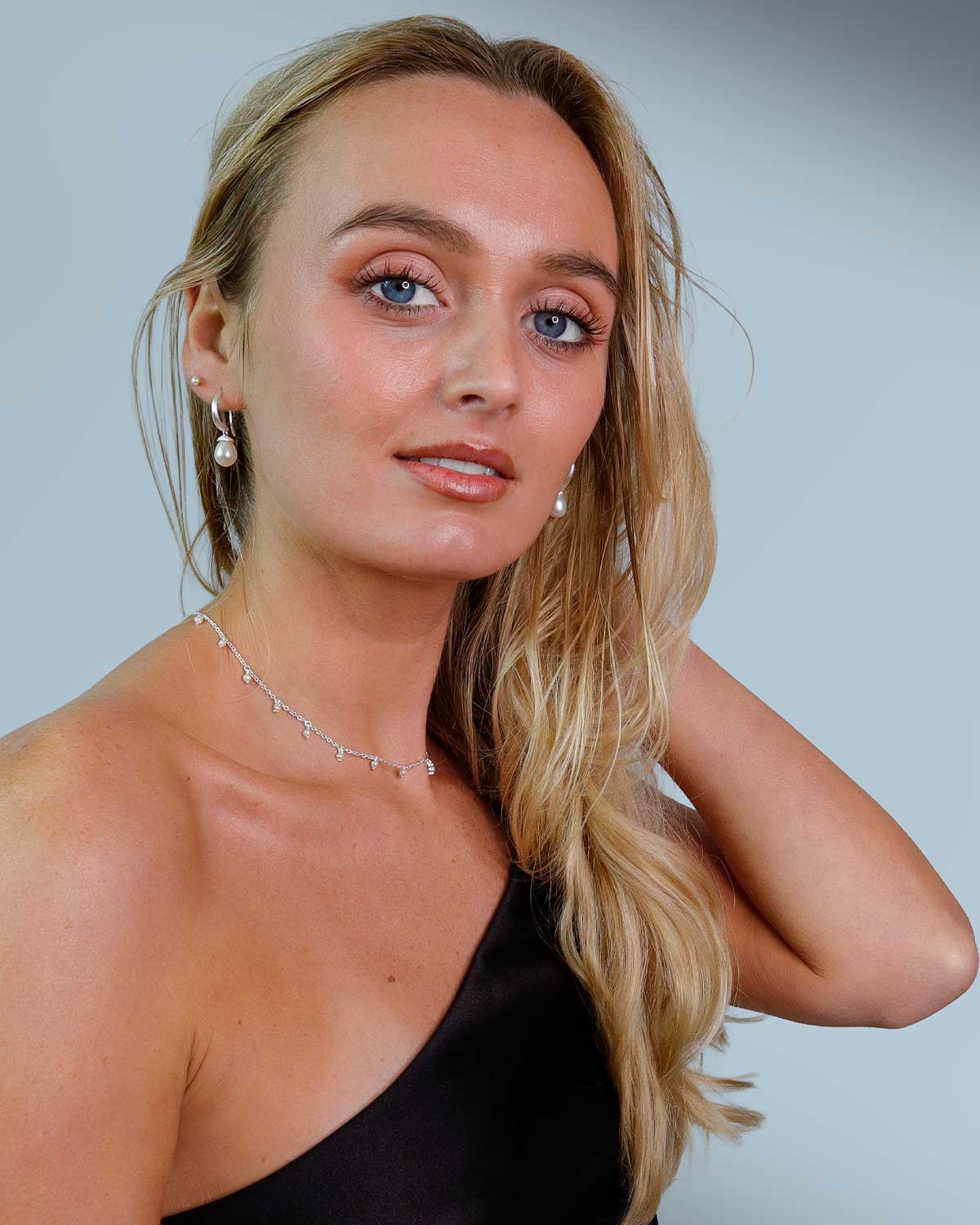 Model wearing handcrafted sterling silver drop earrings with natural pearls, suitable for June birthstone gifts