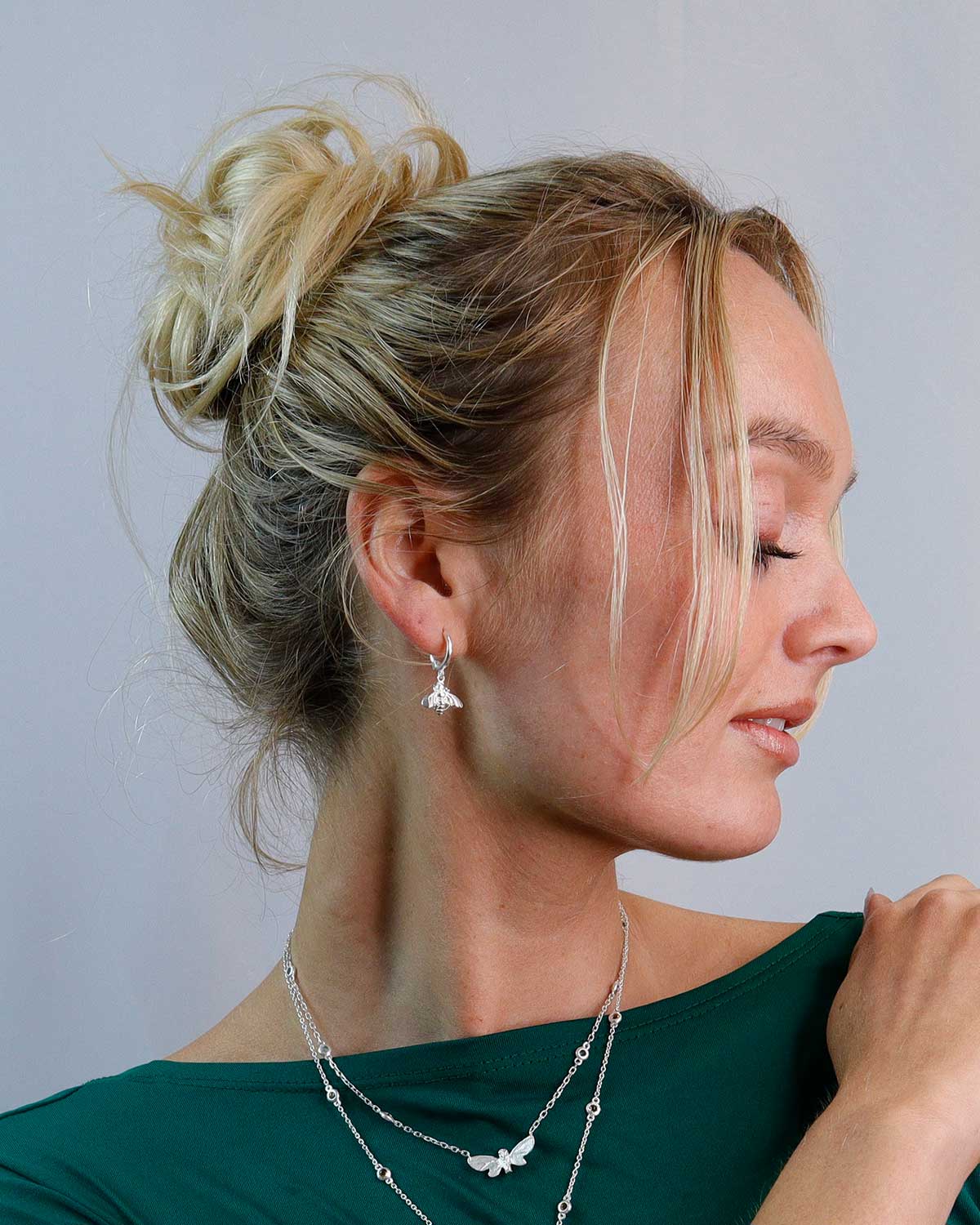 Silver mini hoops styled with other jewelry, featuring bee motifs and polished finish