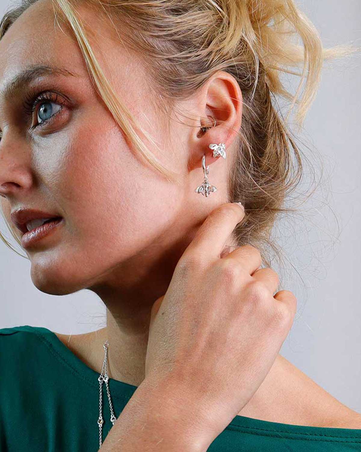 Model wearing silver mini hoop earrings with bee motifs for a subtle statement