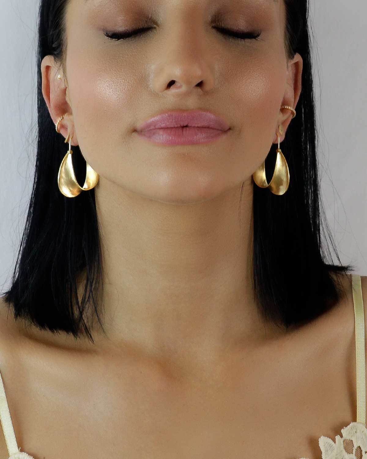 Close-up of twisted gold hoop earrings with a polished finish