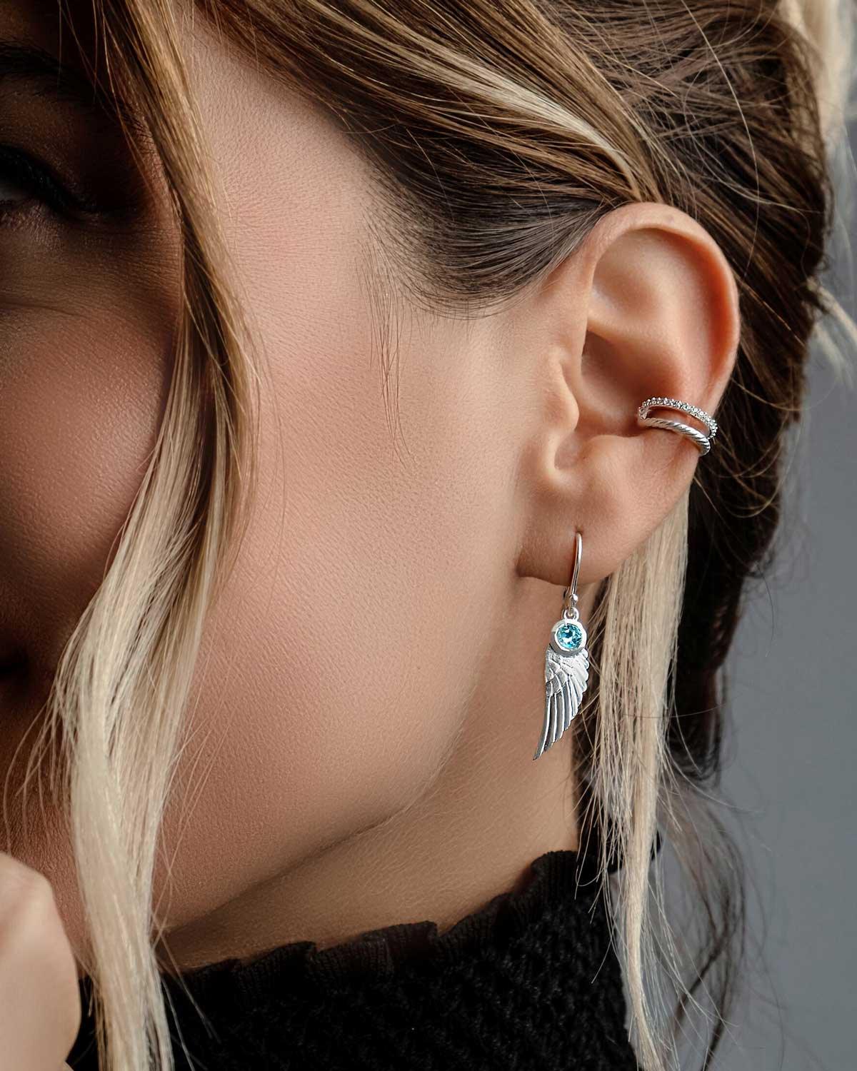 Model wearing silver angel wing earrings with natural gemstones