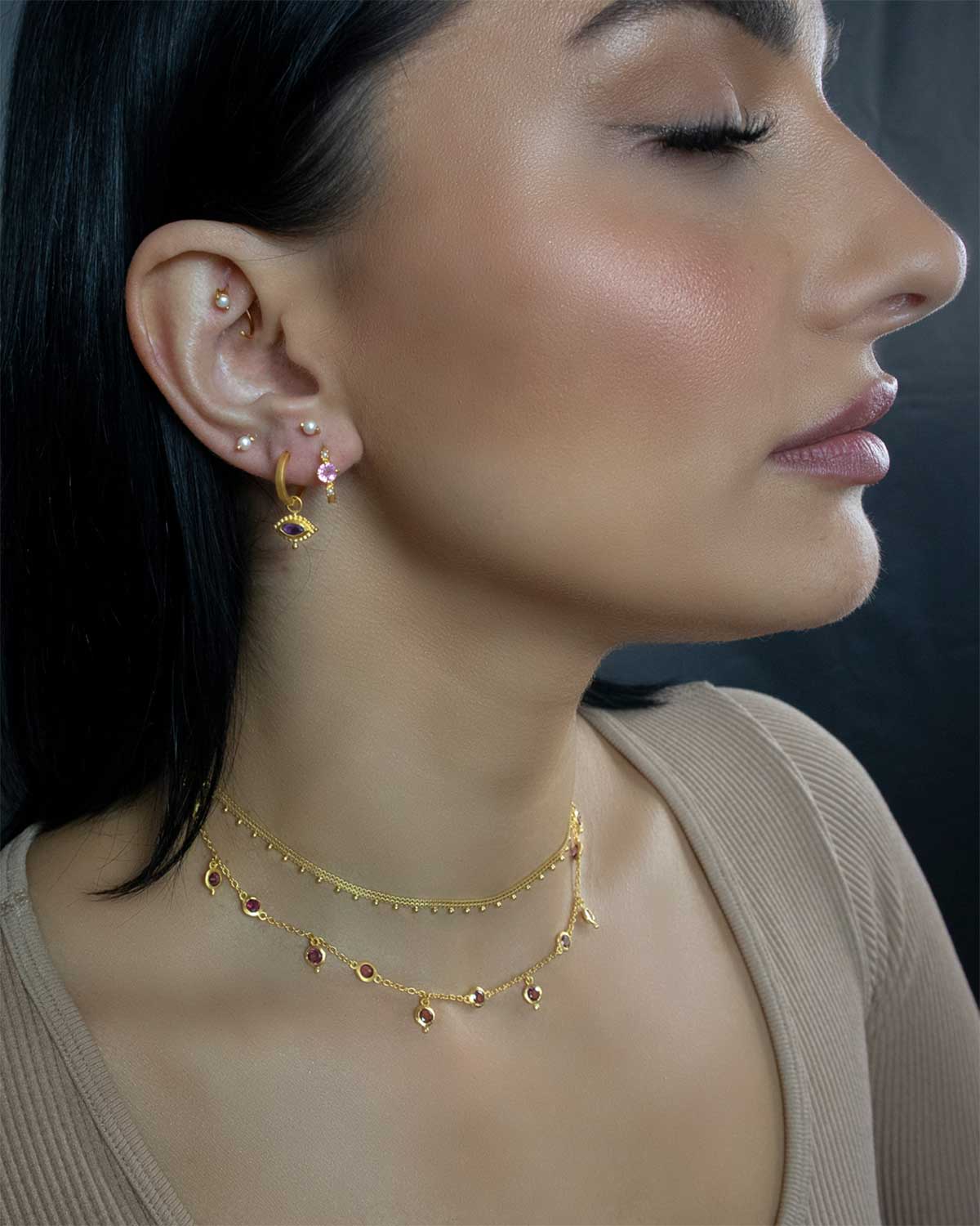 Close-up of gold necklace featuring rhodolite garnet gemstone detailing