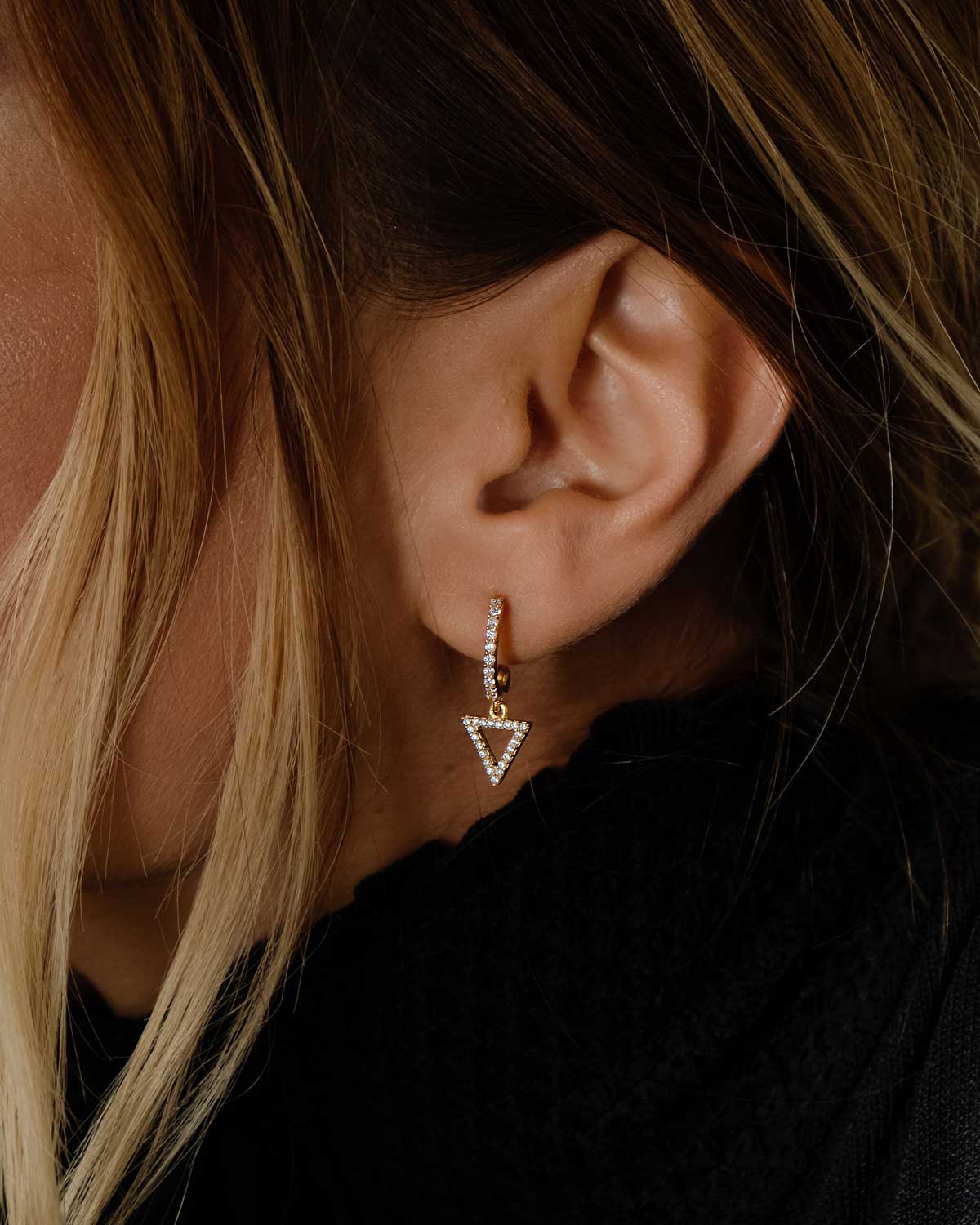 Side angle of gold mini hoops with crystal embellished triangle charm