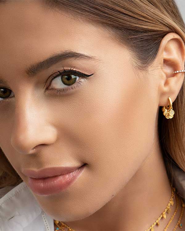 Close-up of gold mini hoops with hammered charms and small crystals