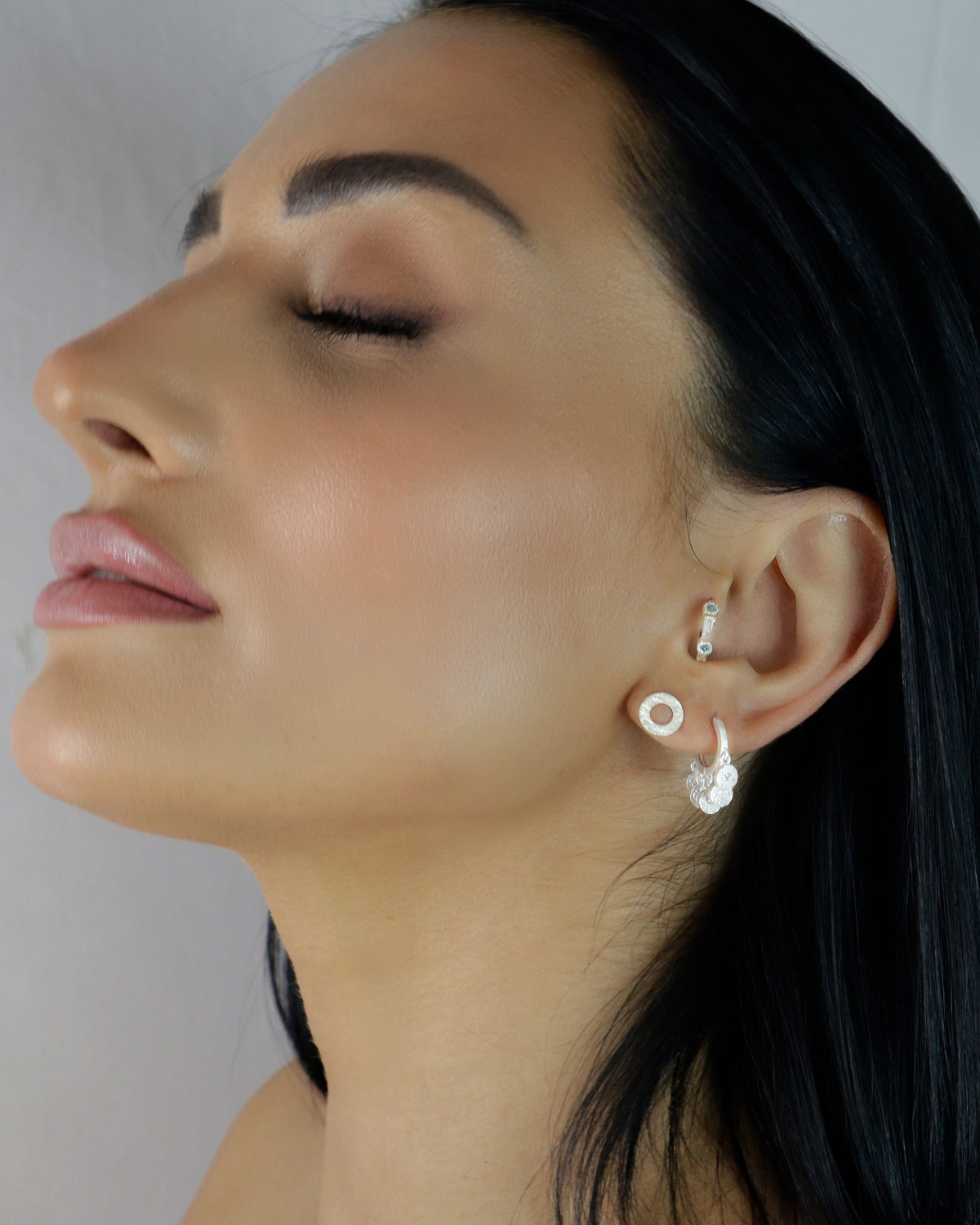 Model wearing gold mini hoop earrings with multiple charm details