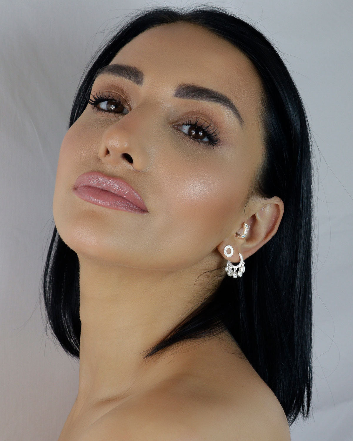Silver mini hoop earrings with a lightly hammered texture and charm accents