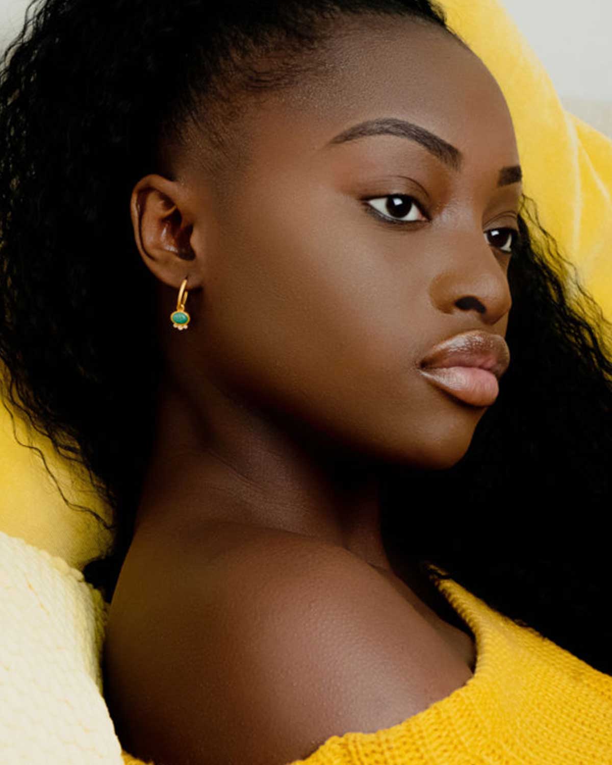 Model wearing mini hoop earrings with rainbow moonstone charm