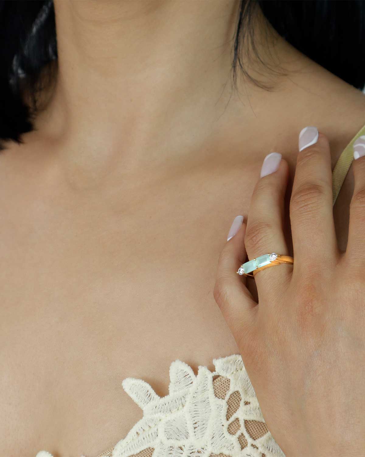 Model wearing gold ring with aqua chalcedony baguette gemstone