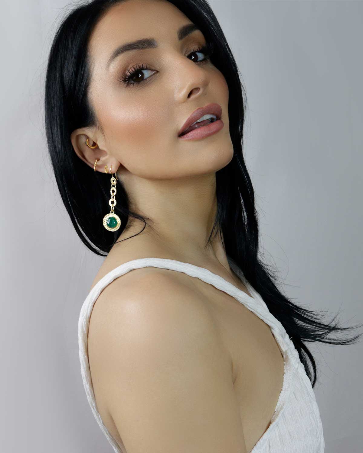 Model wearing emerald green gemstone drop earrings in gold