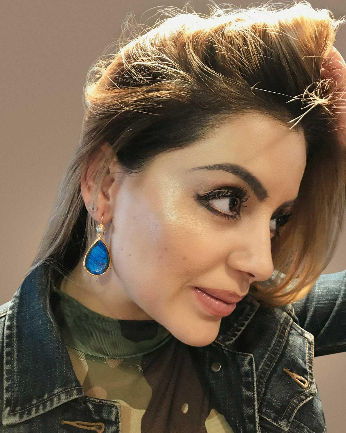 Model wearing gold earrings with teardrop labradorite stones