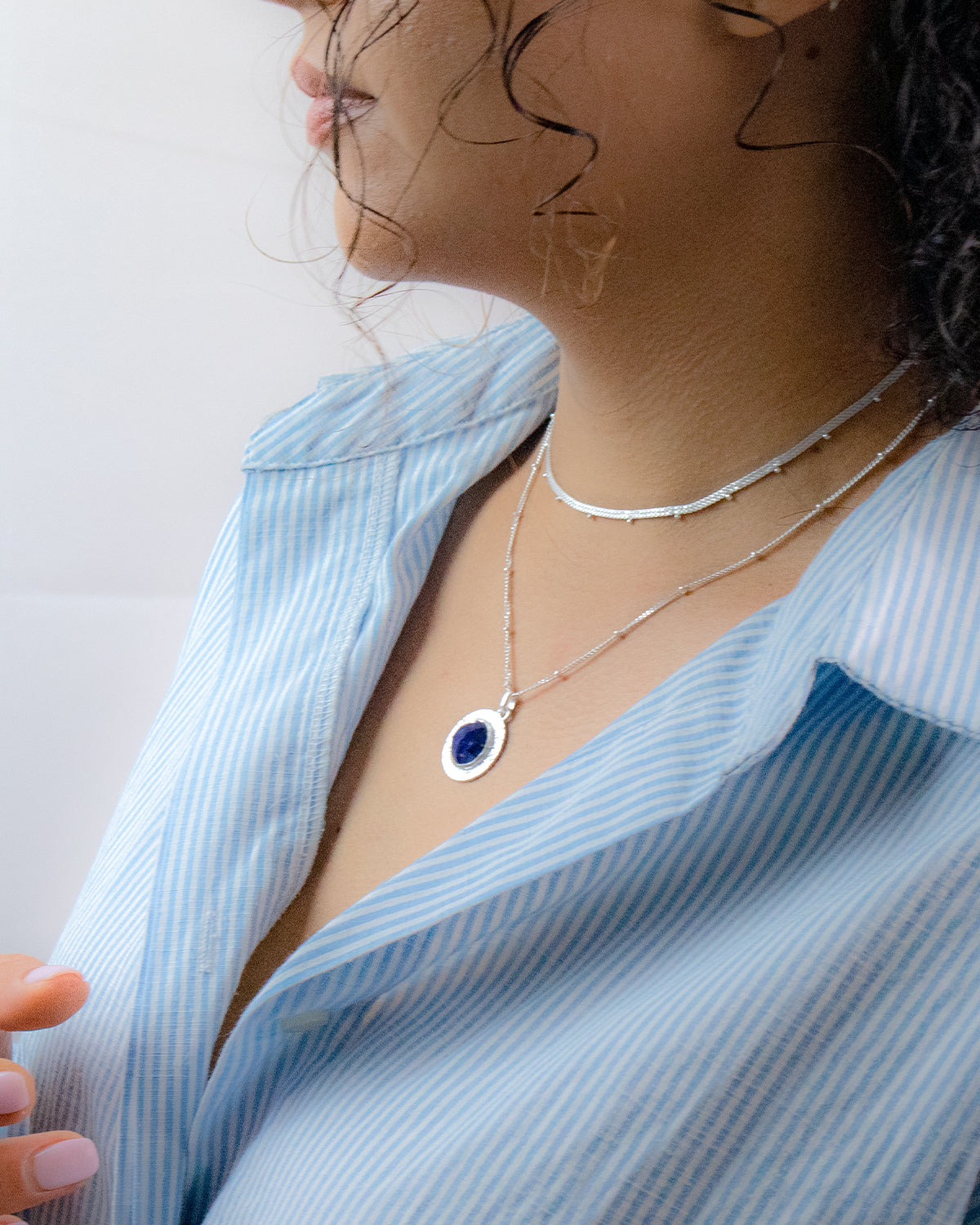 Model wearing sterling silver necklace with circular lapis lazuli pendant