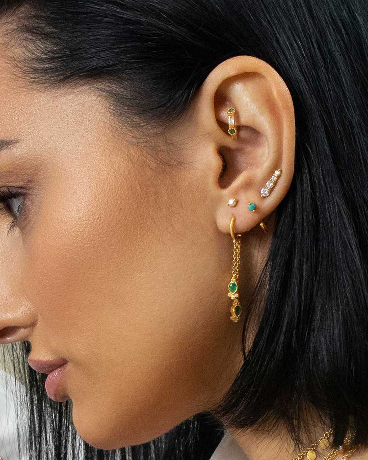 Model wearing mini gold stud earring with cubic zirconia crystals