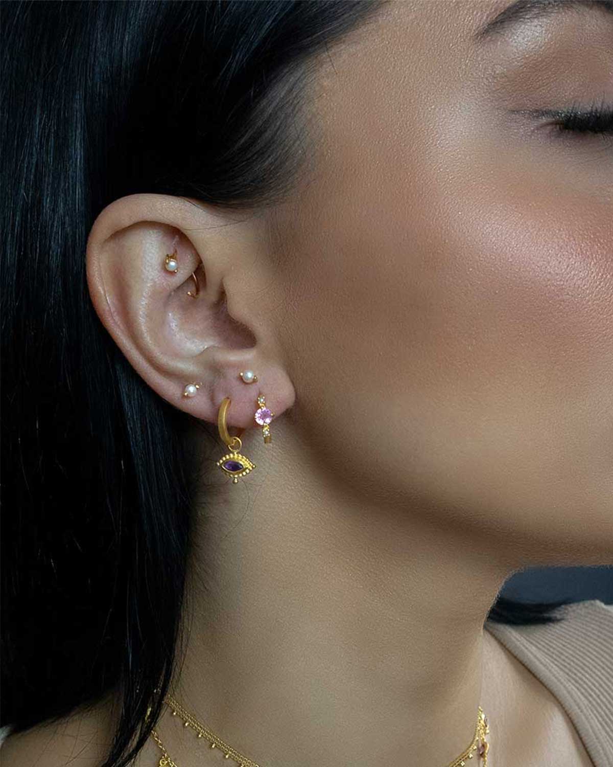 Side view of mini gold stud earrings with a small natural pearl