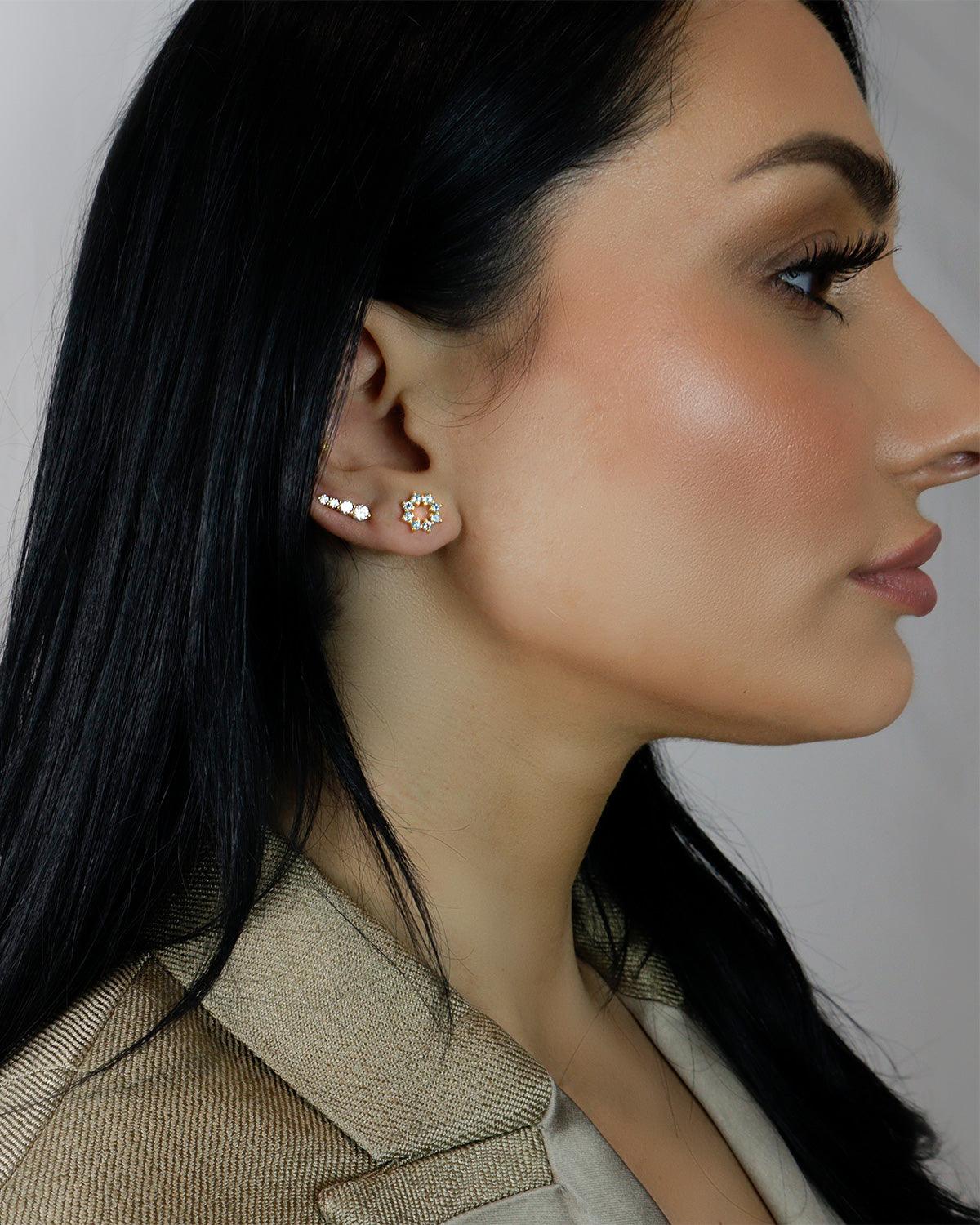 Side view of gold stud earrings with delicate blue topaz gemstones