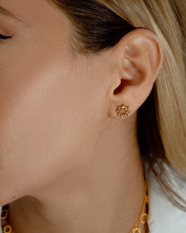 Close-up of silver stud earrings with sparkling blue topaz stones