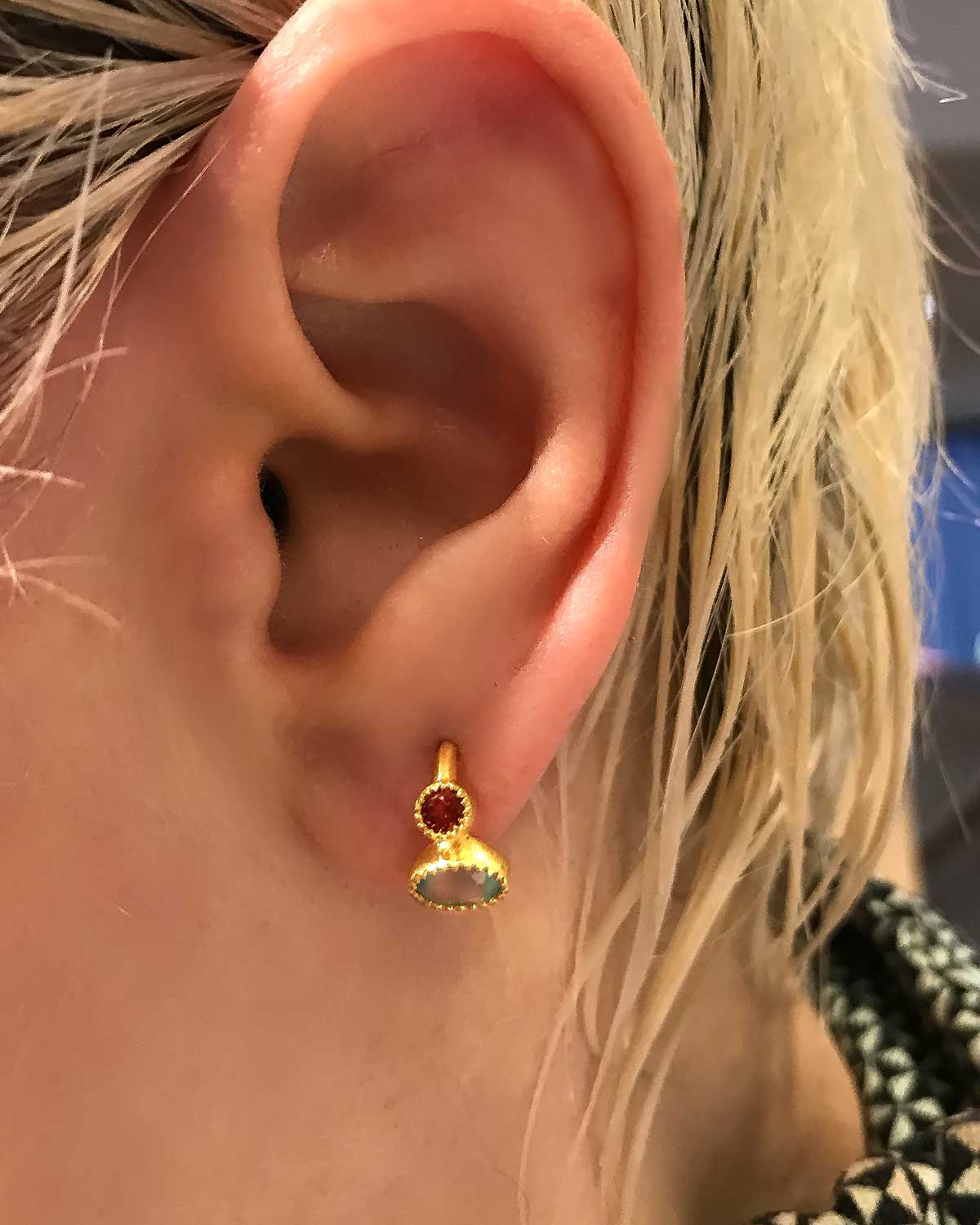 Detailed view of garnet and aqua calcedony gemstones on gold mini hoops