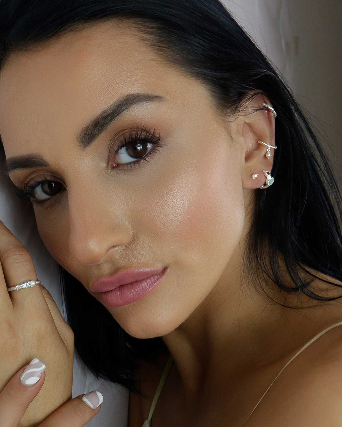 Model wearing silver mini hoop earrings with garnet and aqua gemstones