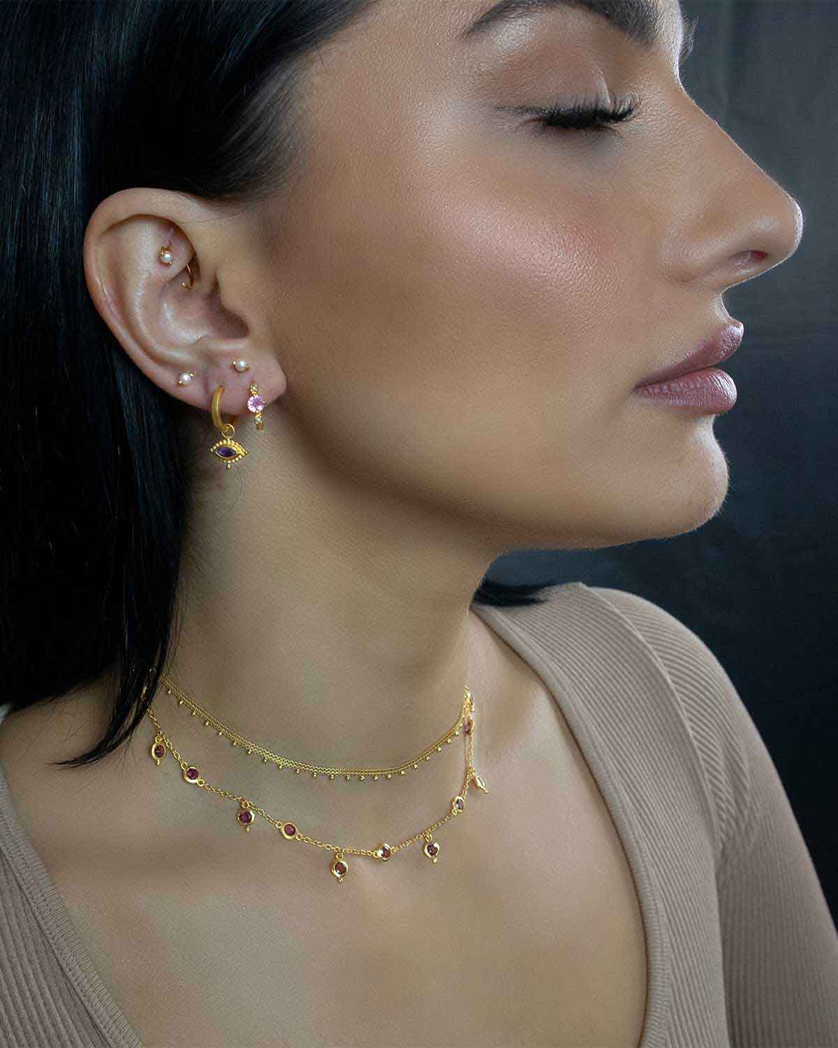 Model wearing mini gold hoop earrings with blue topaz gemstones and pearls
