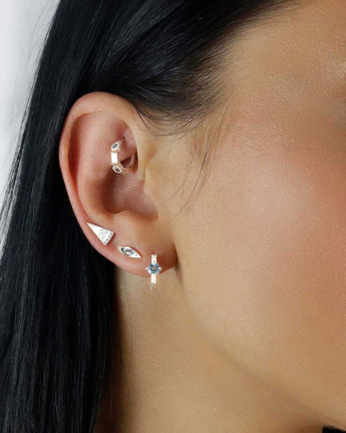 Close-up of silver mini hoops with blue topaz stones and pearls