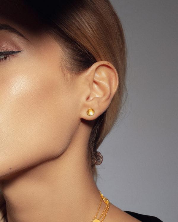 Close-up of gold stud earrings with a smooth curved design