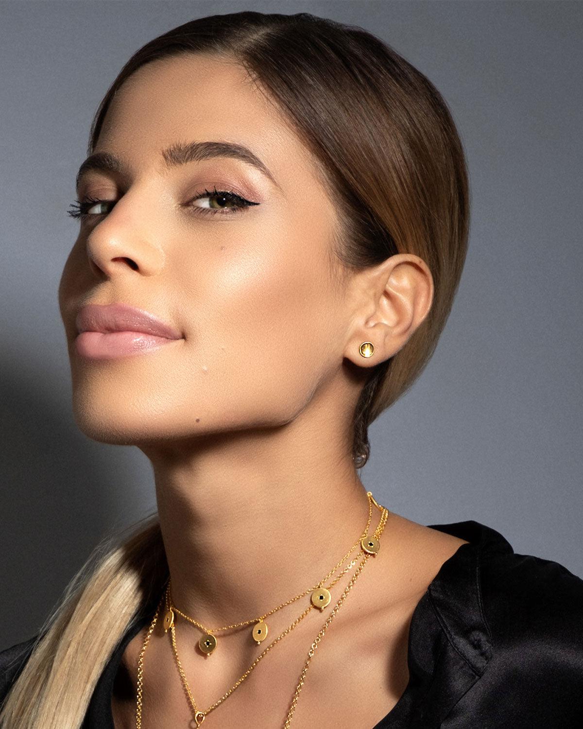 Model wearing gold stud earrings with a simple curved design