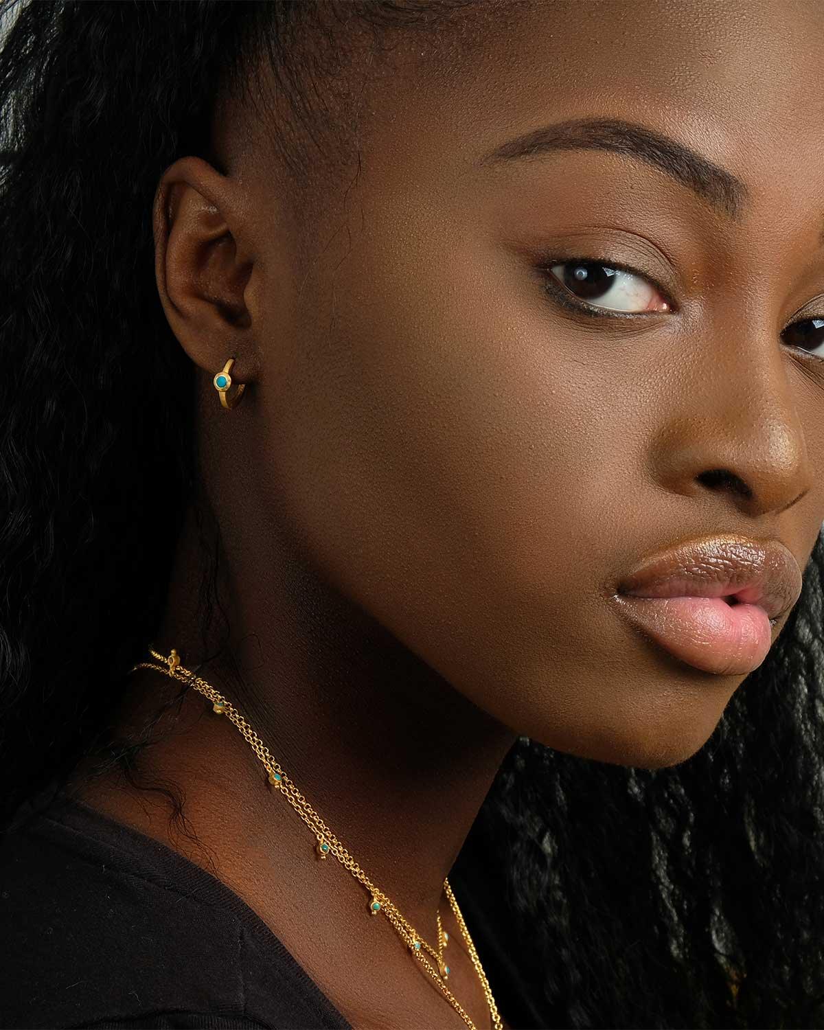 Model wearing gold mini hoop earrings with labradorite gemstones