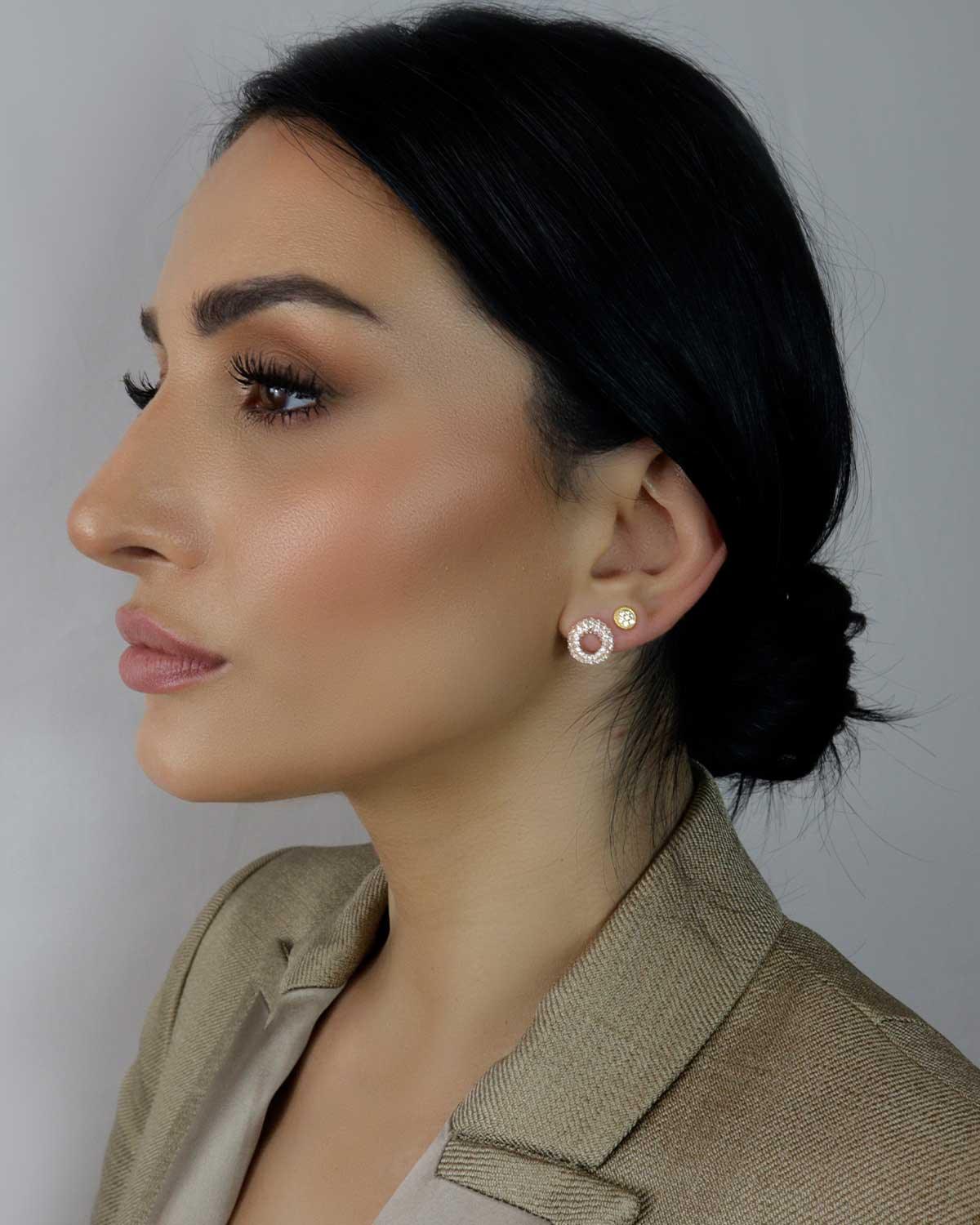 Model wearing spherical gold stud earrings with sparkling cubic zirconia