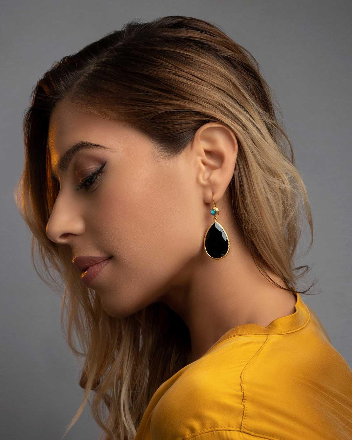 Close-up of teardrop gold earrings with black spinel gemstone