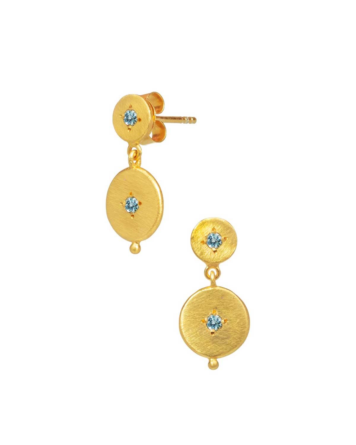 Gold gemstone earrings styled with studs in a stacked look